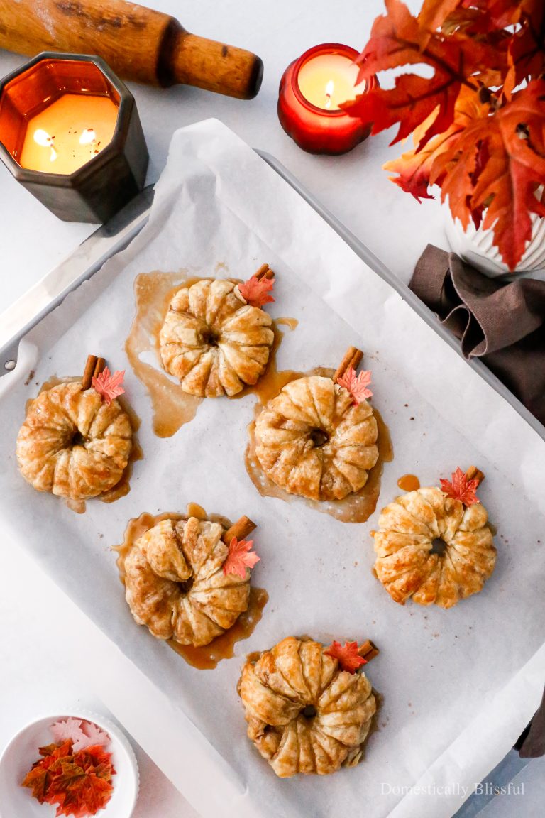 These Apple Cinnamon Pastry Donuts are filled with fresh apple slices, surrounded by puff pastry, covered in cinnamon sugar, drizzled with caramel sauce, and topped with a cinnamon stick and edible maple leaf.