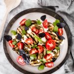 This Grilled Eggplant Salad is marinated, grilled, and topped with whipped ricotta, pesto, quartered tomatoes, and fresh herbs.