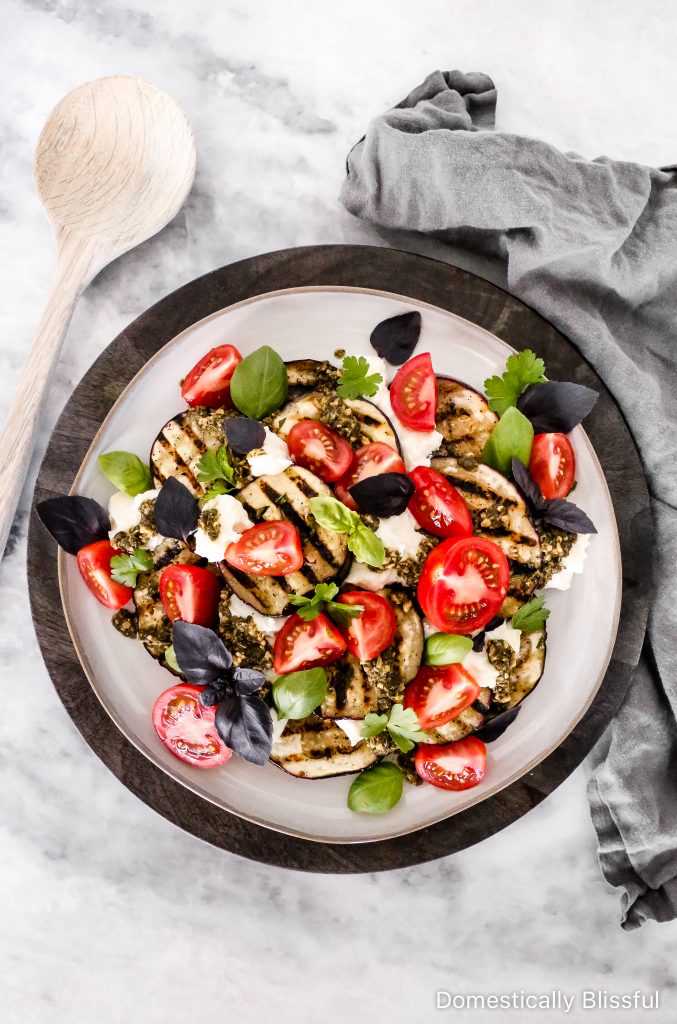 This Grilled Eggplant Salad is marinated, grilled, and topped with whipped ricotta, pesto, quartered tomatoes, and fresh herbs.