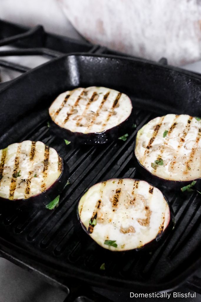 This Grilled Eggplant Salad is marinated, grilled, and topped with whipped ricotta, pesto, quartered tomatoes, and fresh herbs.