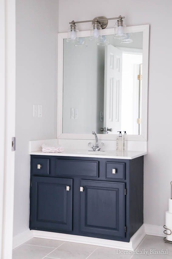 A guest bathroom remodel on a budget with new tile, fresh paint, an updated vanity, & framed mirror.