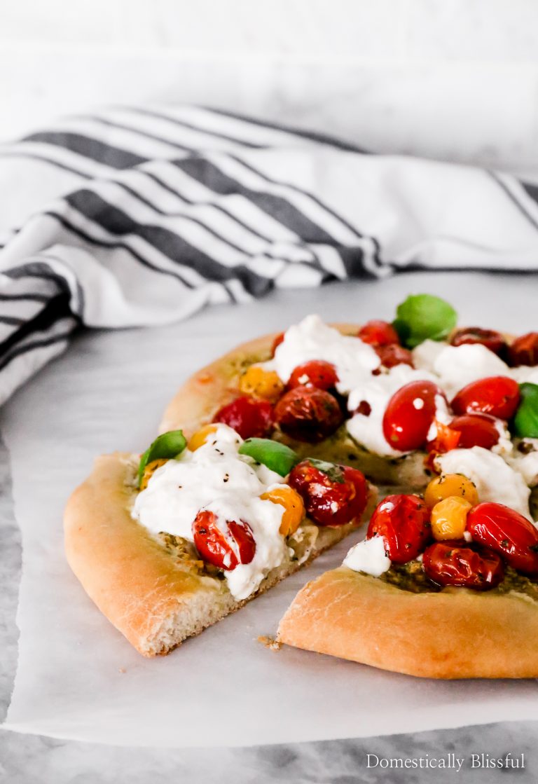 This Burrata Caprese Pizza has a pesto base and is topped with broken burrata that melts into the roasted cherry tomatoes.