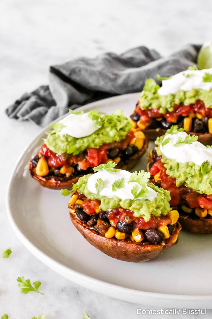 These Loaded Black Bean Taco Sweet Potatoes are covered in seasoned black beans and corn and topped with cheese, sour cream, salsa, guacamole, cilantro, and a squeeze of lime.