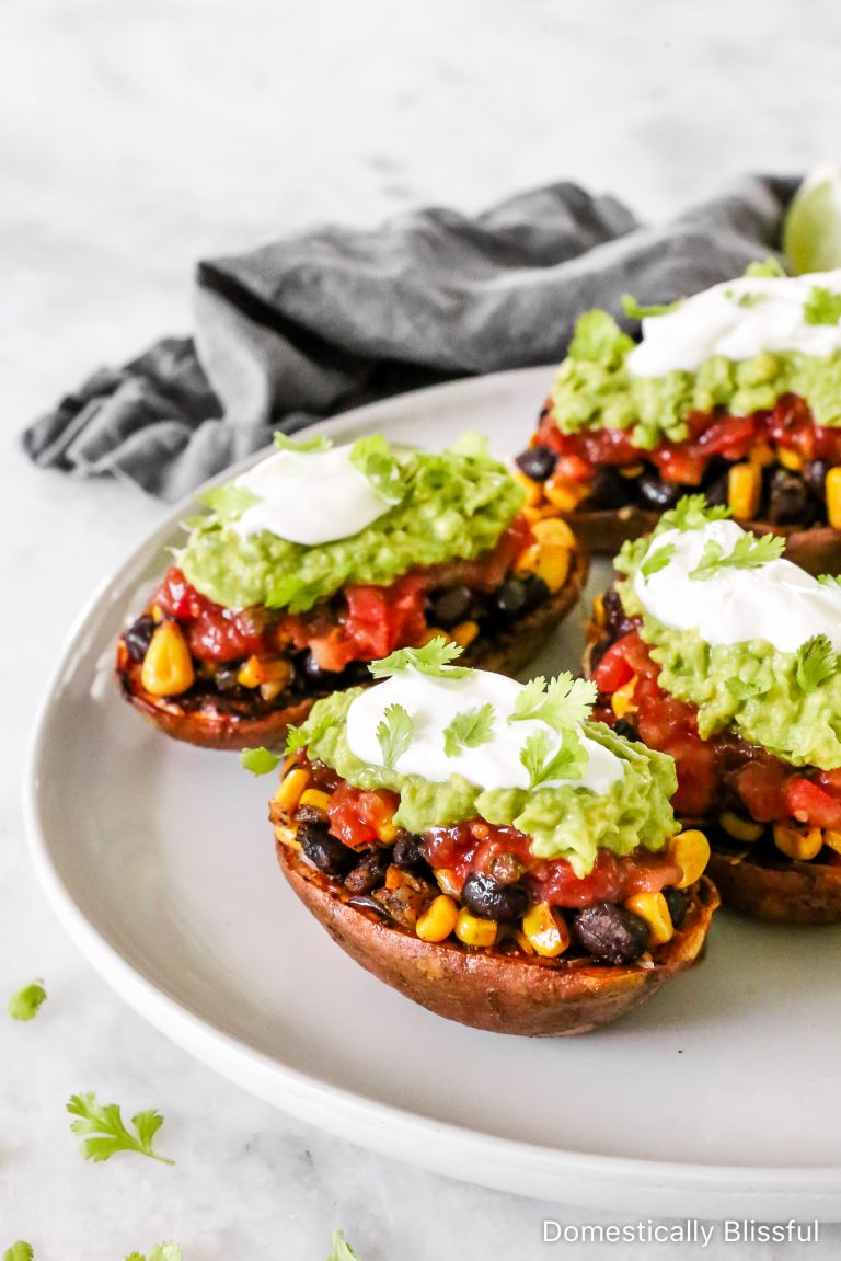 These Loaded Black Bean Taco Sweet Potatoes are covered in seasoned black beans and corn and topped with cheese, sour cream, salsa, guacamole, cilantro, and a squeeze of lime.