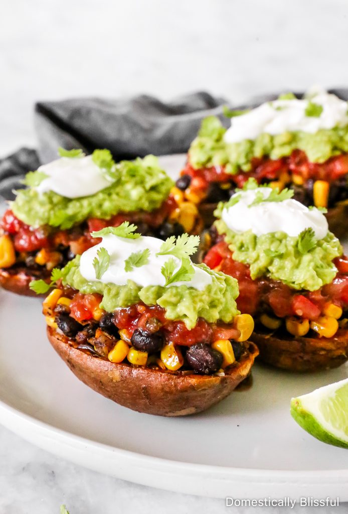 These Loaded Black Bean Taco Sweet Potatoes are covered in seasoned black beans and corn and topped with cheese, sour cream, salsa, guacamole, cilantro, and a squeeze of lime.