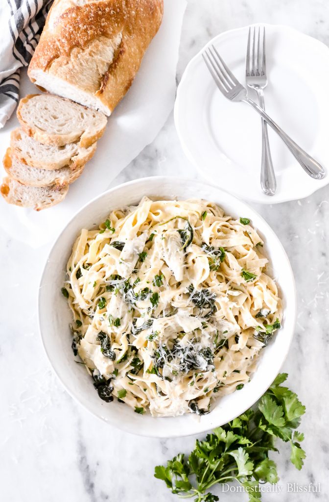 This Spinach Artichoke Fettuccini is made with fresh fettuccini topped with a creamy sauce filled with marinated artichoke hearts and spinach and topped with fresh parsley and grated parmesan.