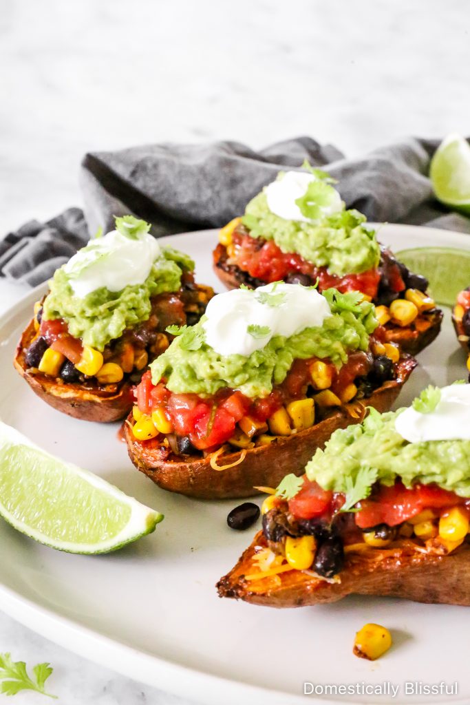 These Loaded Black Bean Taco Sweet Potatoes are covered in seasoned black beans and corn and topped with cheese, sour cream, salsa, guacamole, cilantro, and a squeeze of lime.