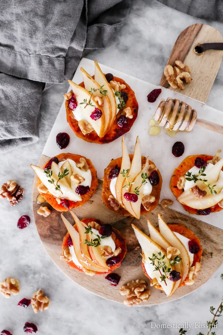 These Pear & Whipped Goat Cheese Sweet Potato Rounds are topped with slices of pear, whipped goat cheese, walnuts, dried cranberries, fresh thyme, and a drizzle of honey.